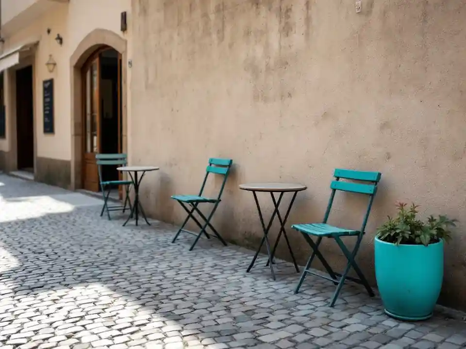 Small round cafe tables and folding chairs on an empty cobbled terrace
