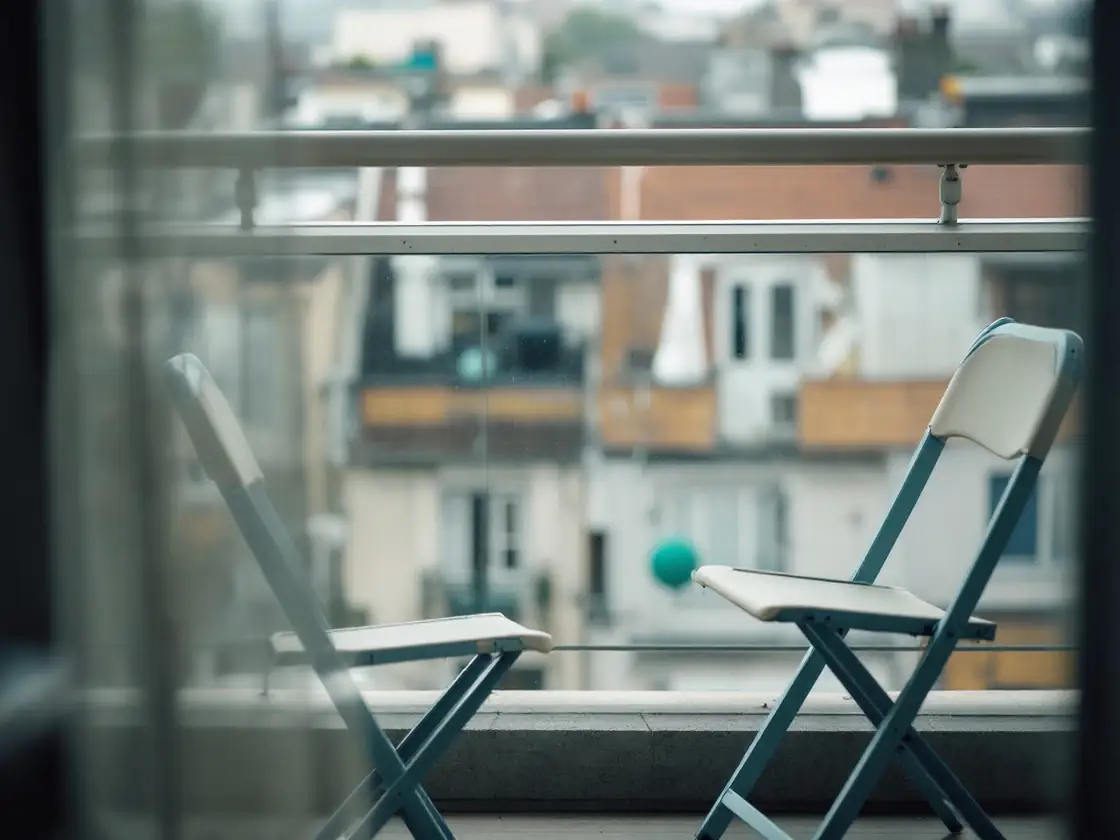 Two folding chairs on a small apartment balcony in morning light