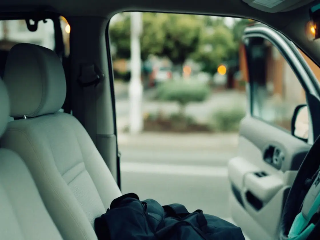 A small overnight bag on the passenger seat of a parked car