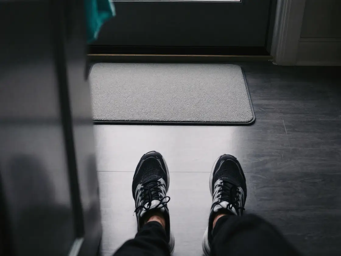 Feet in running shoes on a doorstep seen from above