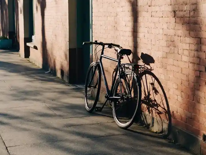 A bicycle leaning against a brick wall in late afternoon sun