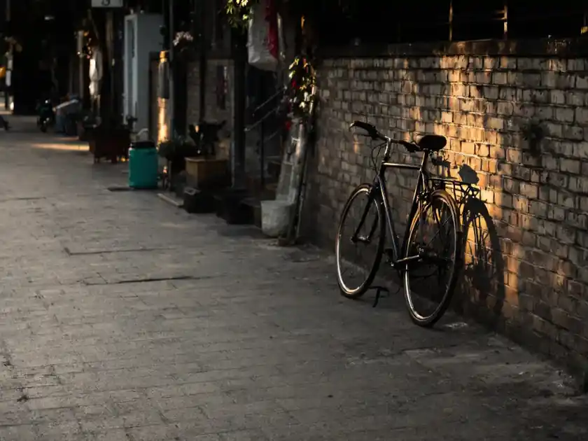 A bicycle leaning against a brick wall in late afternoon sun