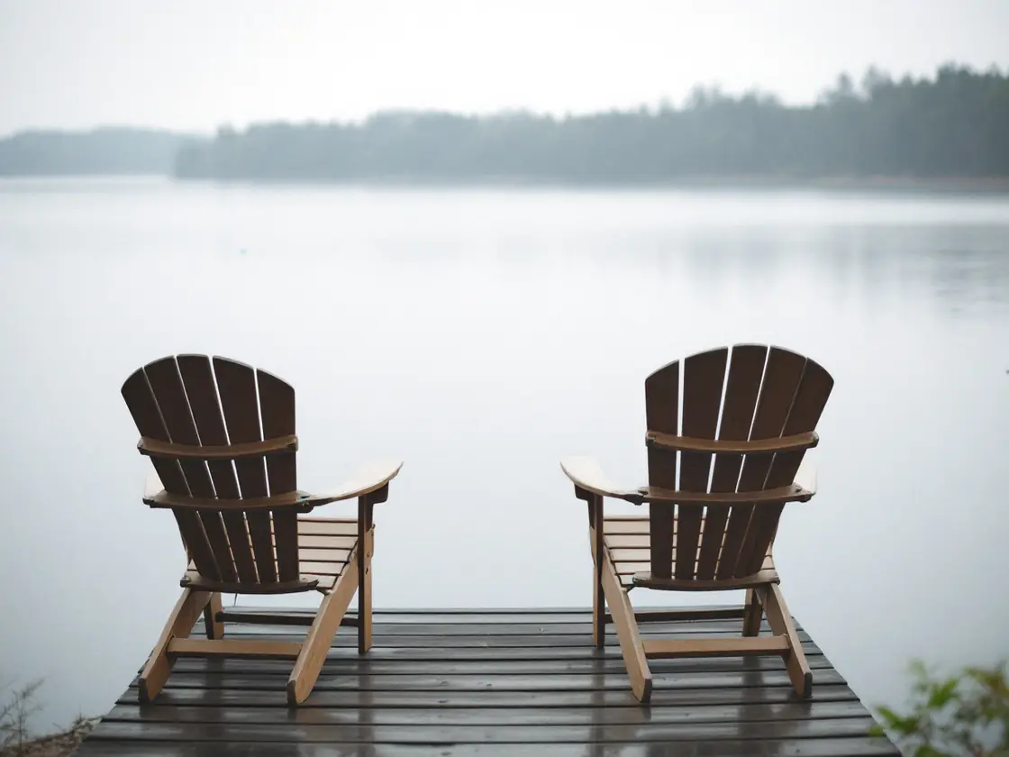 Two empty chairs facing a lake in soft overcast morning light
