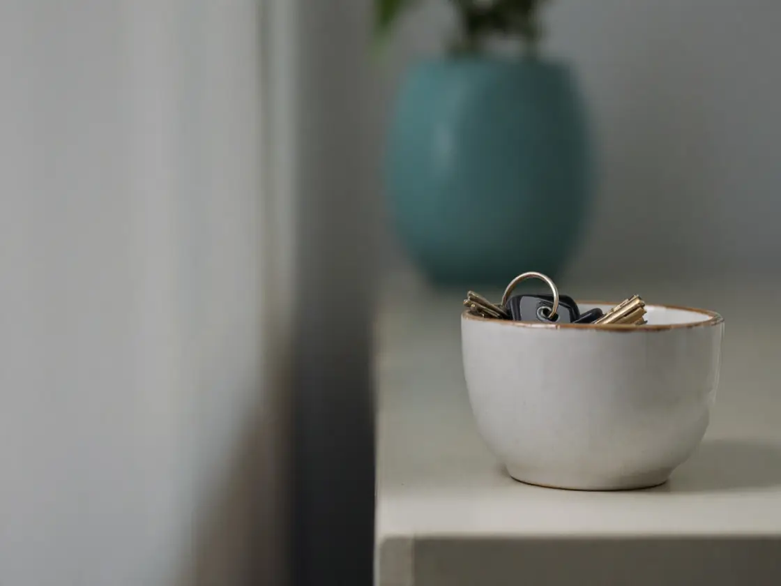 A set of keys in a ceramic bowl on an entry table