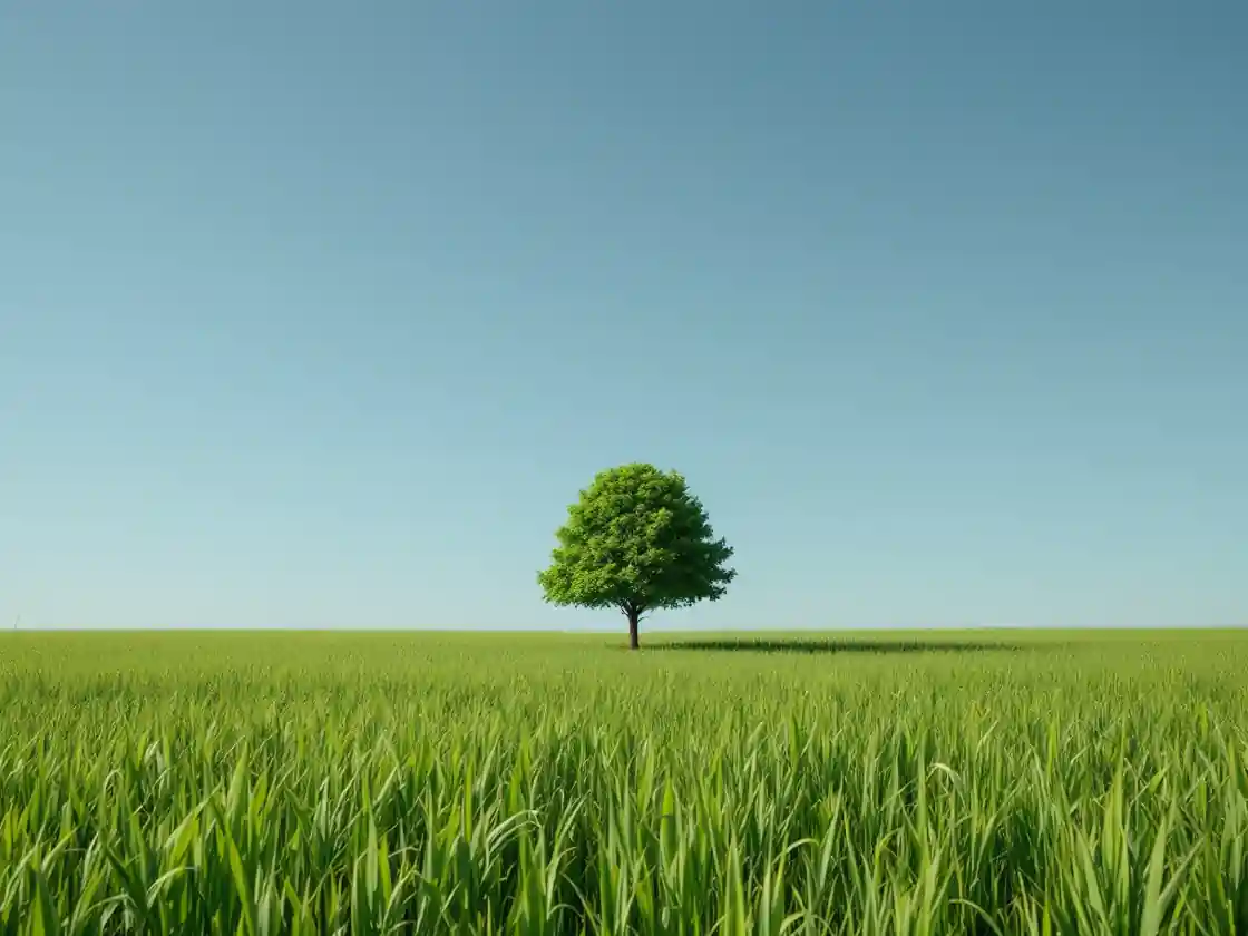 A wide green meadow with one tree under a clear blue sky